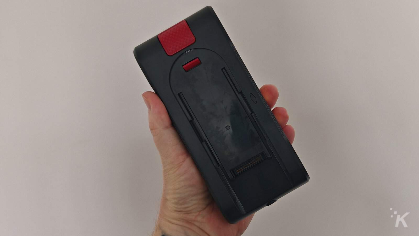 Person holding a black handheld device, bottom view.