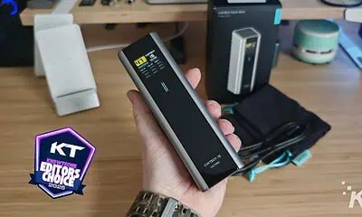 Hand holding portable battery power bank on desk.